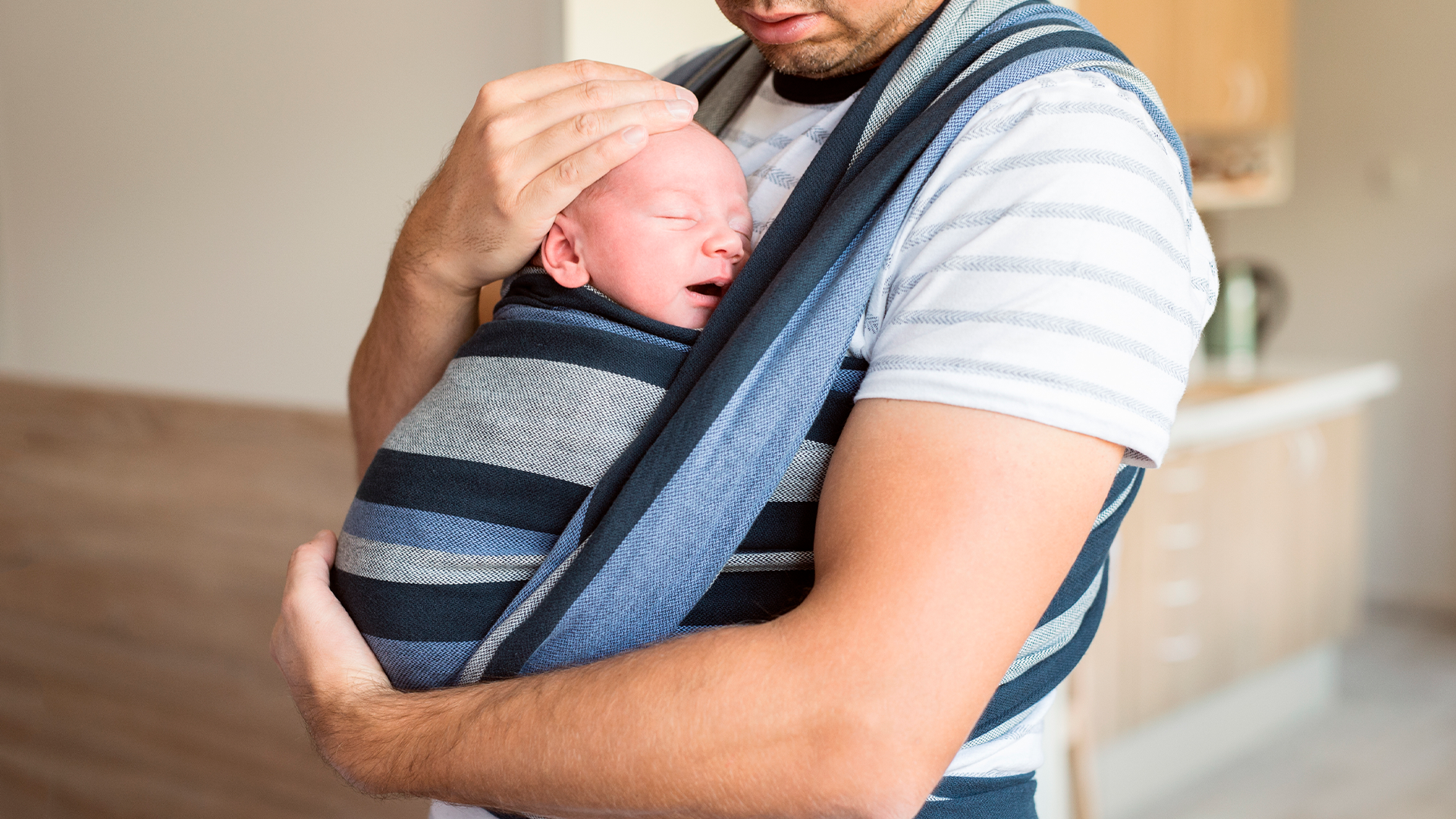 Papá realiza porteo con su bebé mediante un fular.