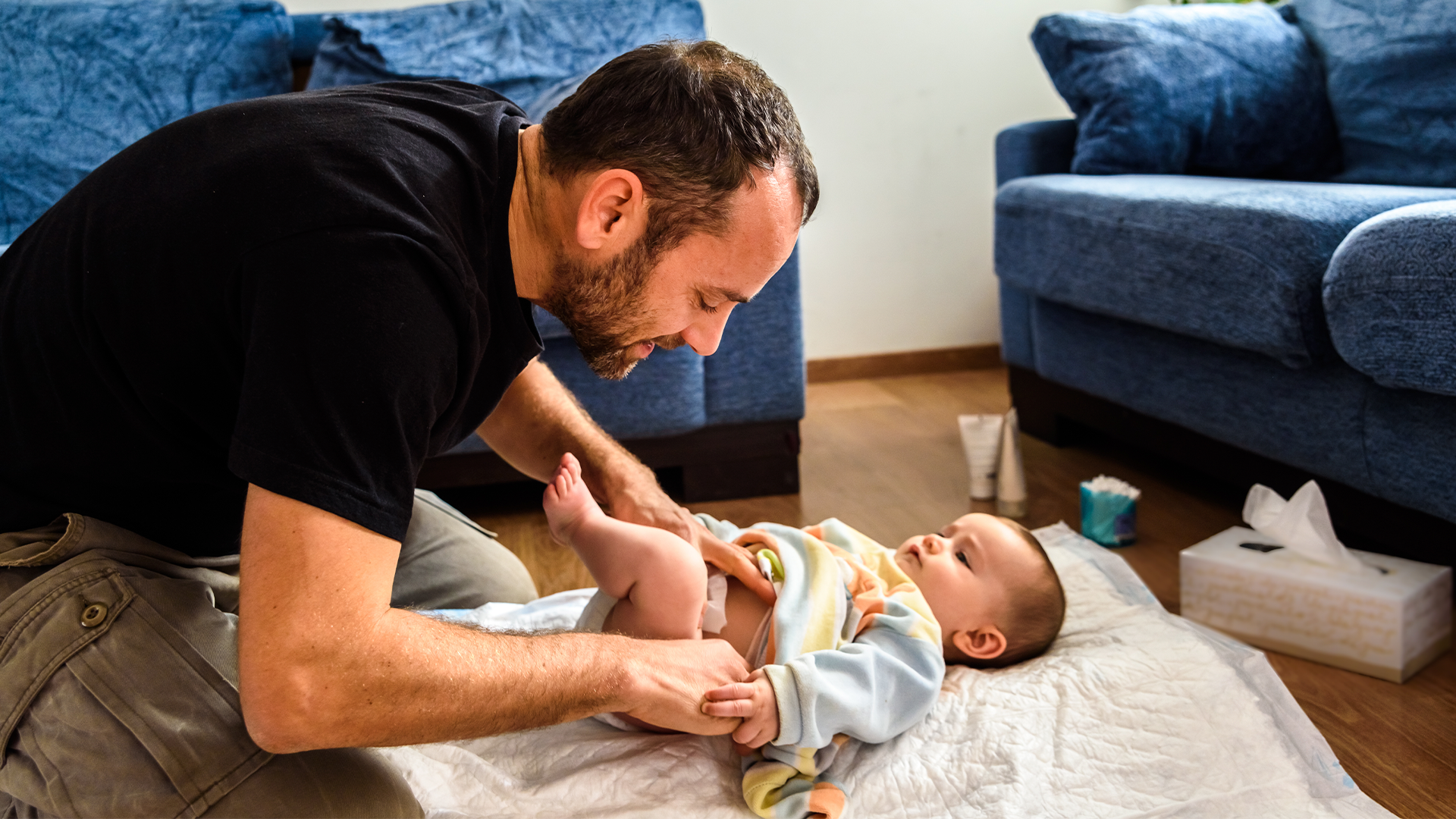 Papá cambiando el pañal a su bebé, creando un momento de conexión y vínculo emocional en la rutina diaria