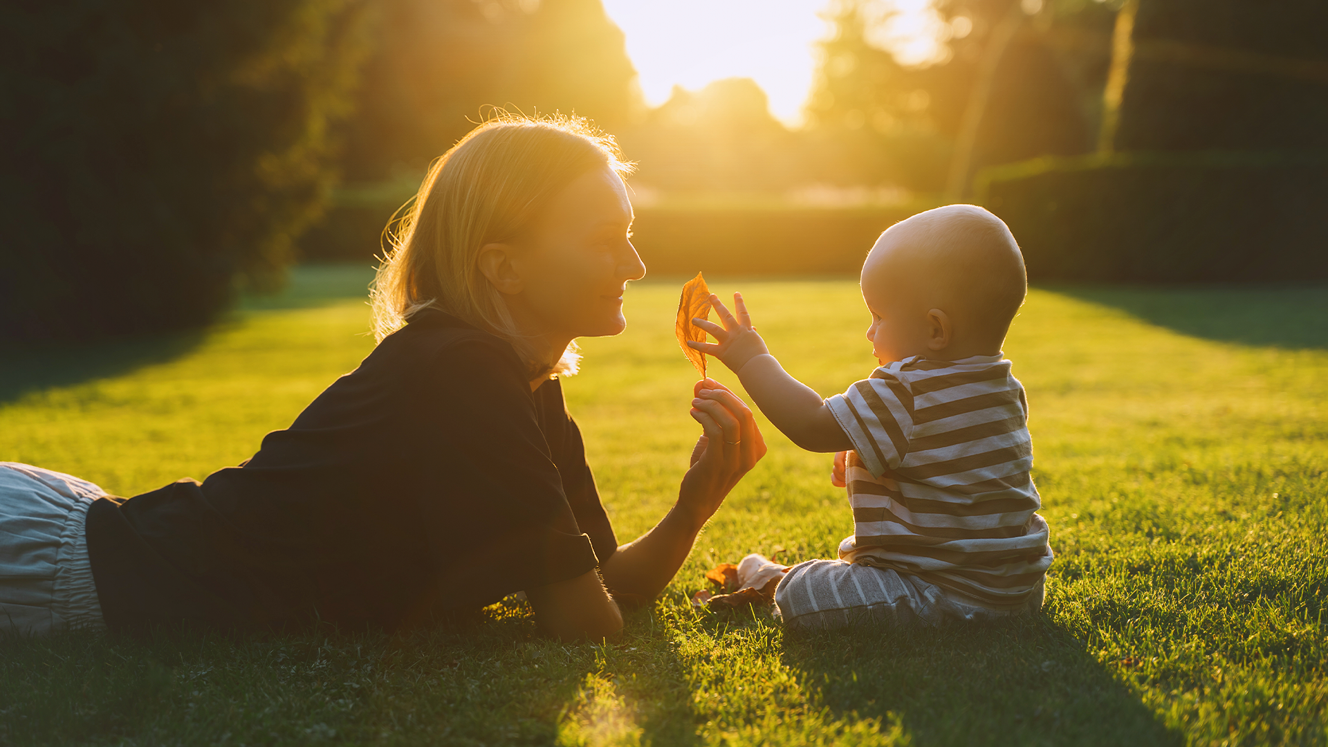Mamá y bebé haciendo actividades sensoriales al aire libre, disfrutando del sol para conectar con la naturaleza en familia