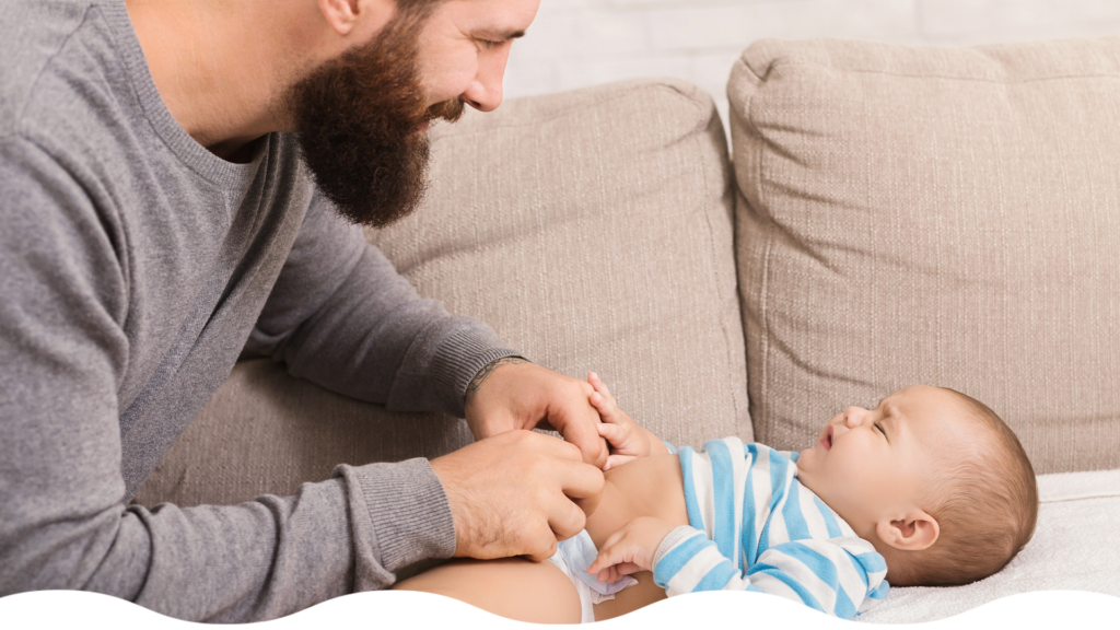 Papá cambiando el pañal a su bebé llorando, manteniéndose tranquilo durante su técnica de cambio de pañal