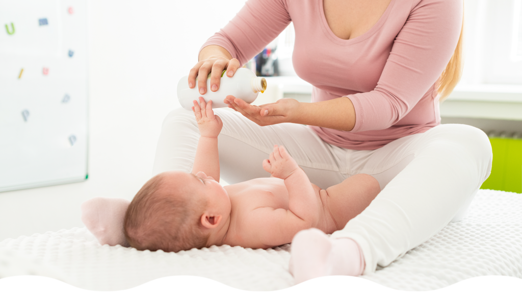 Mamá masajeando suavemente la piel de su bebé y aplicando crema para la dermatitis del pañal, un momento de cuidado y contacto.