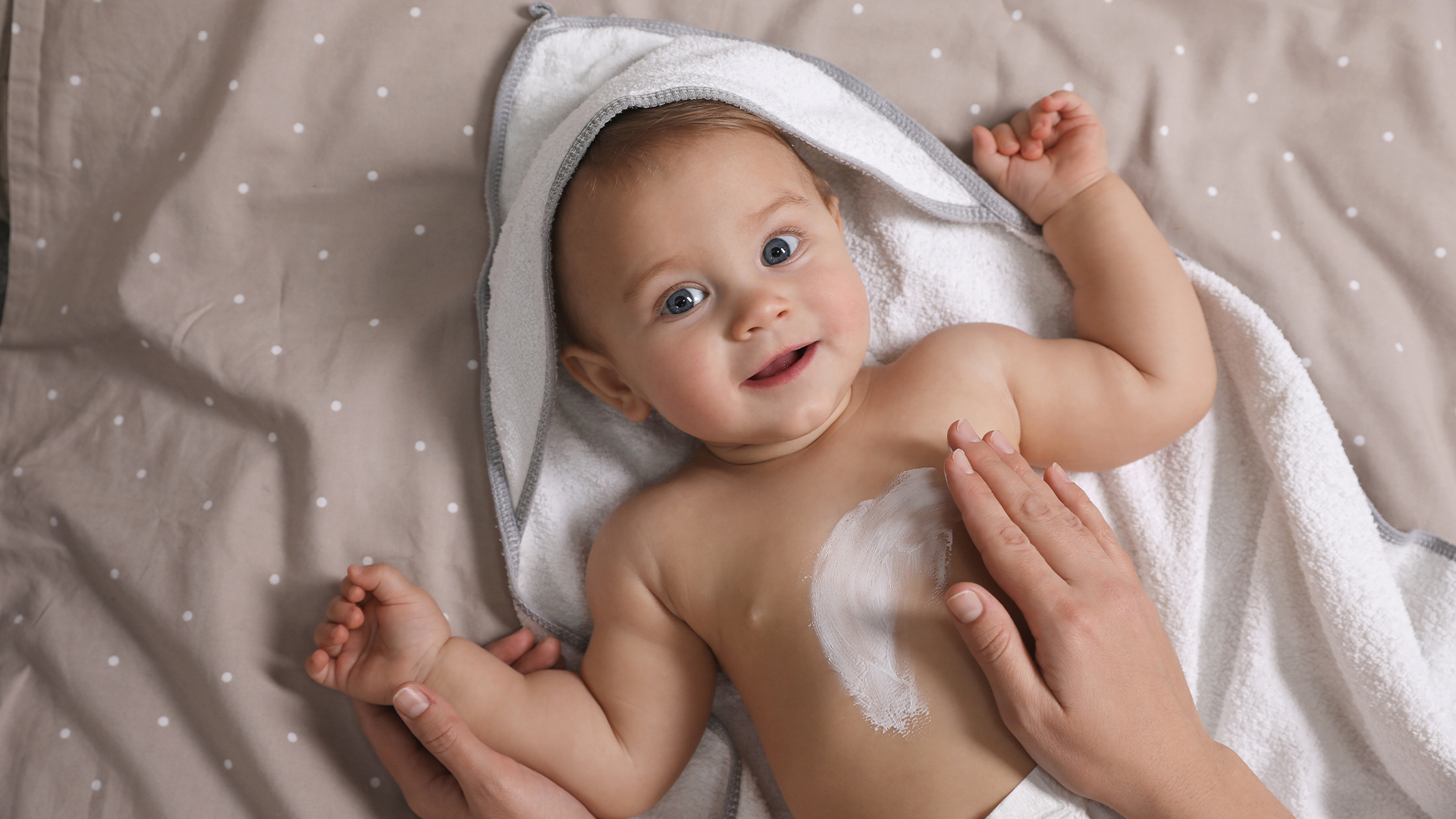 Mamá hidratando la piel de su bebé con productos naturales como parte del cuidado de la piel en verano